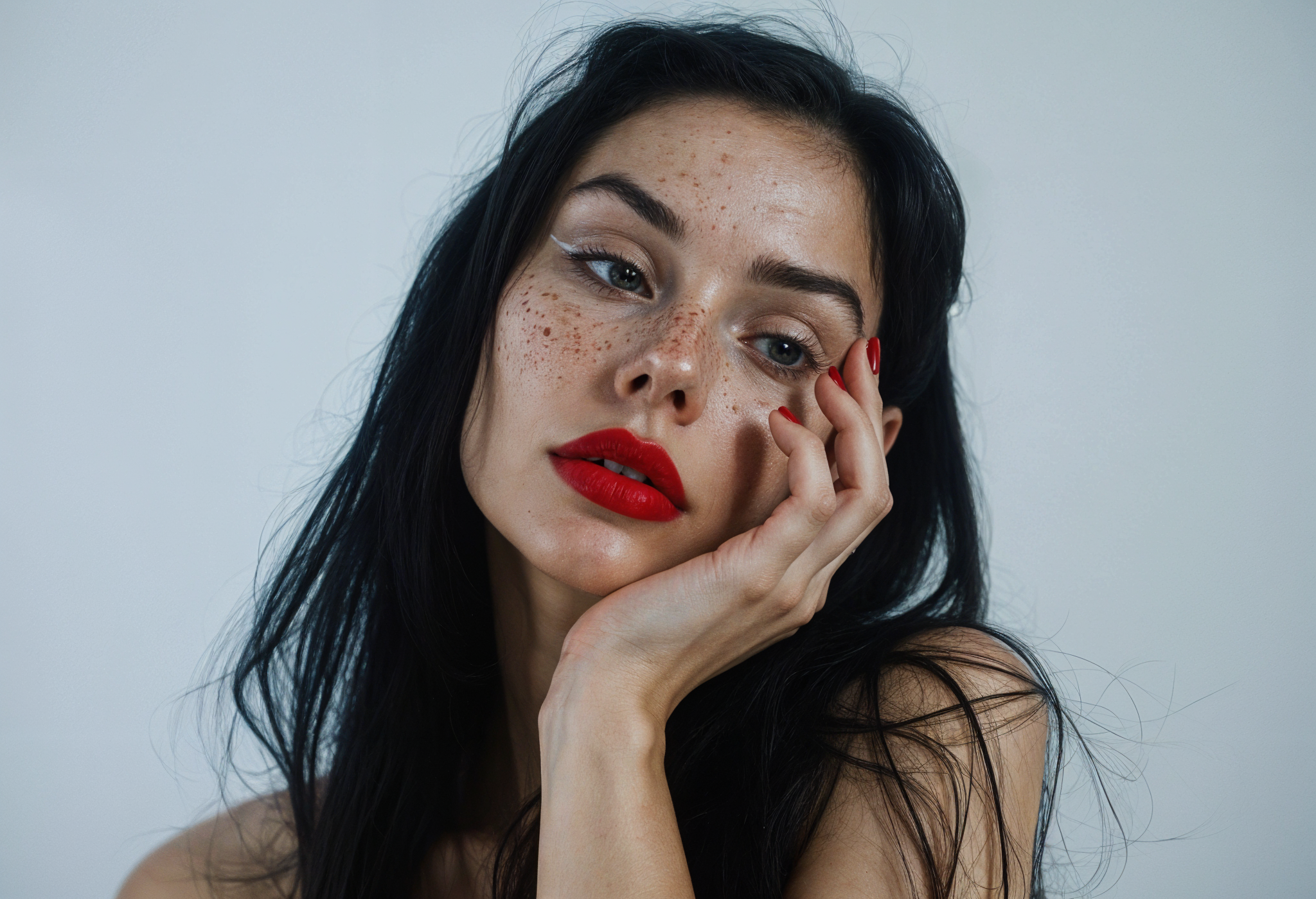 Woman with dark hair and red lipstick touching her face against a plain background.
Before,  After comparison